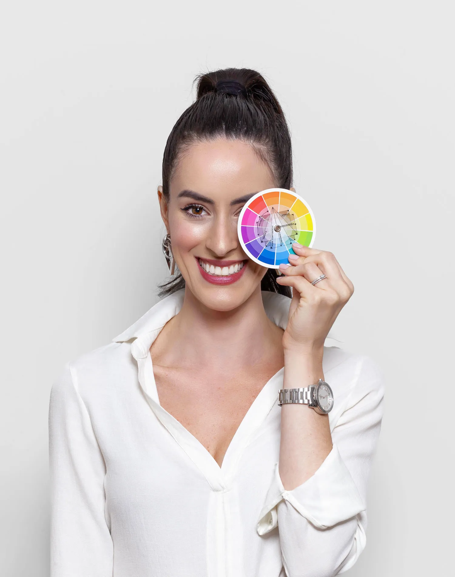 Consultora da Duplica Aí segurando a roda de cores da marca à frente do rosto